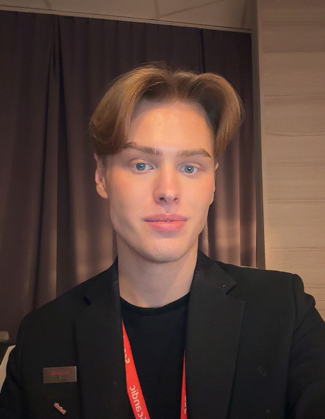 Max en ung kille i mörka kläder med rött nyckeband runt halsen.